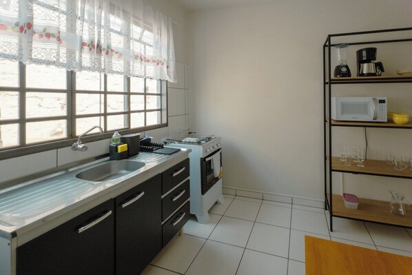 A kitchen with a window, a sink, a stove, a microwave, and a coffee maker.