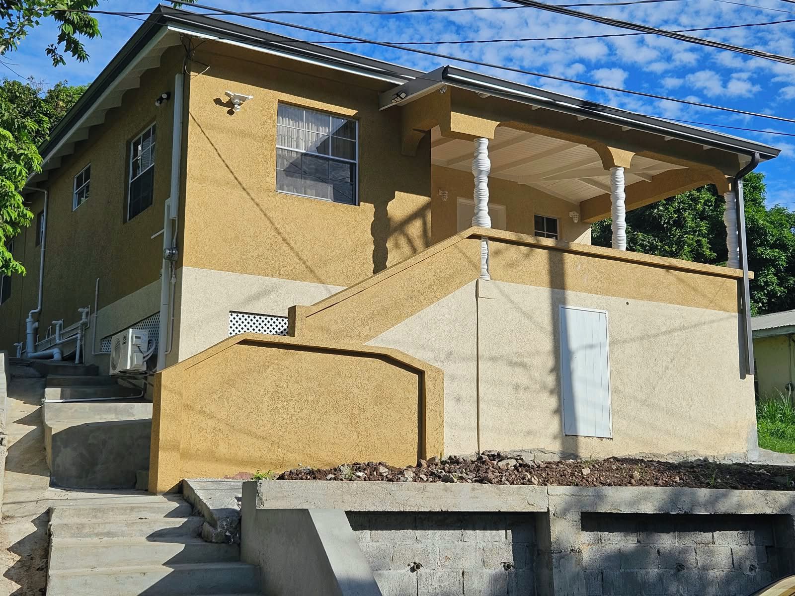Une maison à deux étages avec un porche et un petit jardin à l’avant.