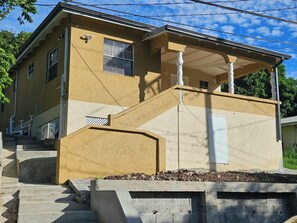 A two-story house with a covered porch and a small front yard. - Synergy Suites Mt. Gay (Saint George)