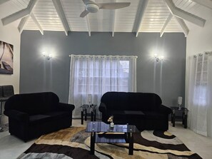A living room with two black sofas, a coffee table, and a patterned rug. - Synergy Suites Mt. Gay (Saint George)