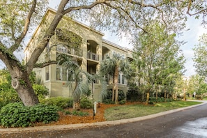 A multi-story building with balconies, surrounded by mature trees and a well-maintained lawn. - Half a Mile to the Pier and Village! (St. Simons Island)