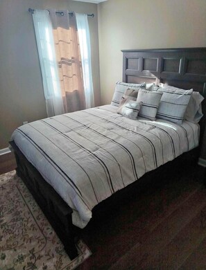 A bedroom with a bed, curtains, and a headboard.