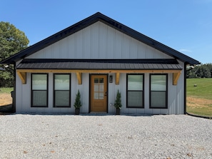 A single-story building with a gabled roof, a front door, and multiple windows.