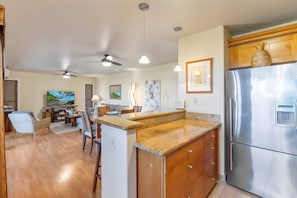 A modern kitchen with a built-in refrigerator, wooden cabinets, and a granite countertop. - Wailea Ekolu | 4BR | Sleeps 12 (Kihei)