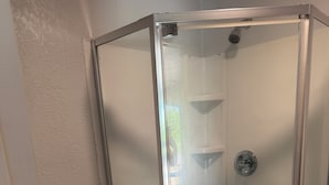 Ein Badezimmer im Eckbereich mit einer gläsernen Dusche, einer Toilette und Holzboden.