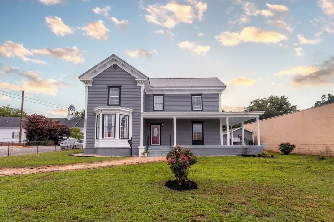 Uma casa de dois andares com varanda, garagem e gramado bem cuidado.