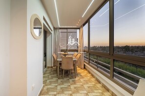 Ein Essbereich mit Tisch und Stühlen, ein großes Fenster mit Blick auf die Stadt und eine Decke mit Einbaustrahlern.
