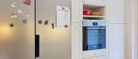 A kitchen with a stainless steel refrigerator, a Bosch oven, and white cabinetry.