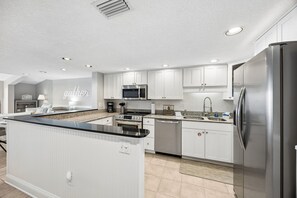 A modern kitchen with white cabinetry, stainless steel appliances, and a central island. - Discover ocean views at Omni 1391 Shipwatch Circle, a 2-bed condo in Fernandina Beach. (Fernandina Beach)