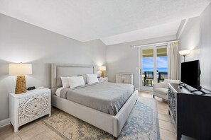 Ein modernes Schlafzimmer mit Bett, Nachttischen, einem Schreibtisch und Blick ins Freie.