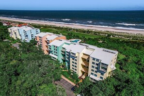 Ein mehrstöckiges Hotel mit Balkonen, einem Pool und Blick auf den Strand.