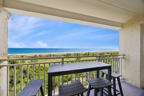 A balcony with a view of the ocean, a table, and two chairs. - Discover ocean views at Omni 1391 Shipwatch Circle, a 2-bed condo in Fernandina Beach. (Fernandina Beach)