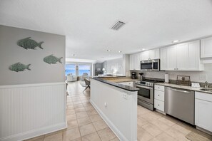 A modern kitchen with white cabinetry, stainless steel appliances, and a view to the outside. - Discover ocean views at Omni 1391 Shipwatch Circle, a 2-bed condo in Fernandina Beach. (Fernandina Beach)