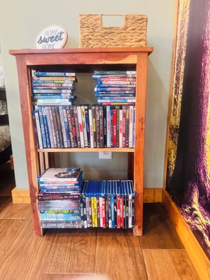 A wooden bookshelf with multiple shelves filled with DVDs and books.