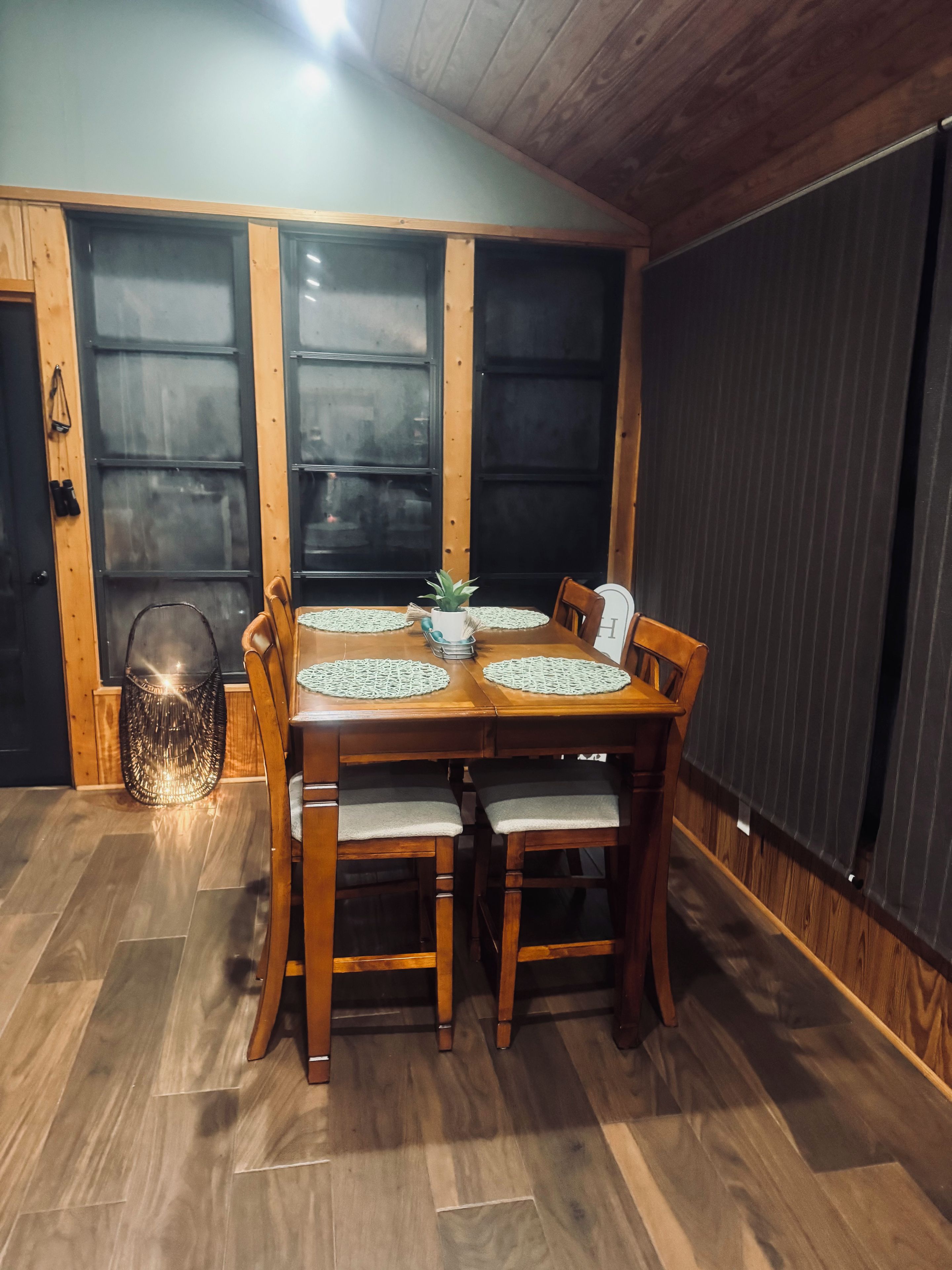 Un comedor con una mesa de madera, cuatro sillas y una planta en maceta.