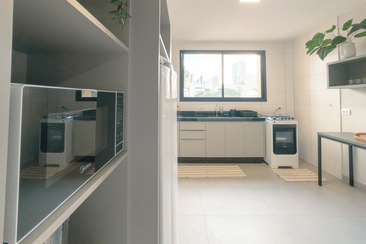 A modern kitchen with white cabinets, a window, and a small table with a plant.