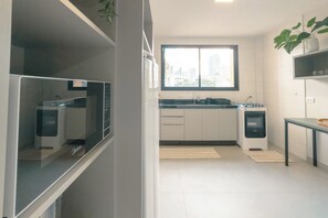 Eine moderne Küche mit weißen Schränken, einem Fenster und einem kleinen Tisch mit einer Pflanze.
