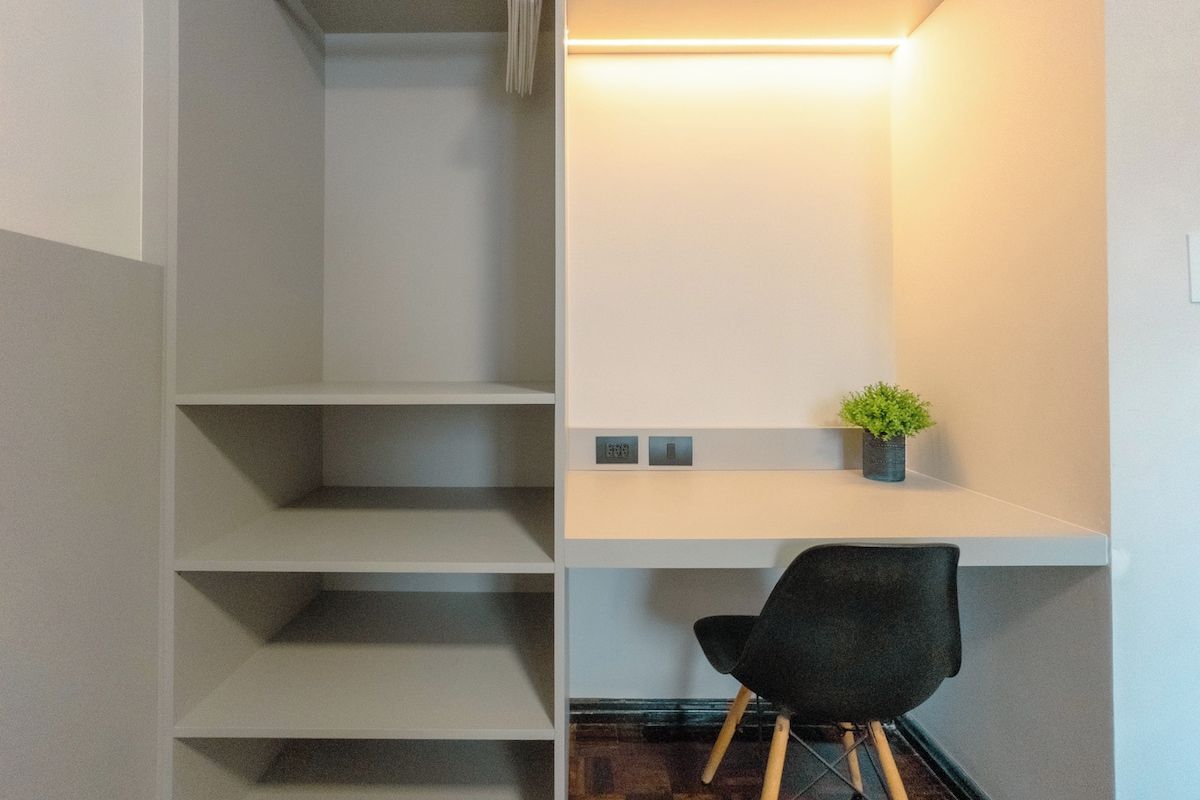 A modern interior with a staircase, a desk with a chair, and a small potted plant.