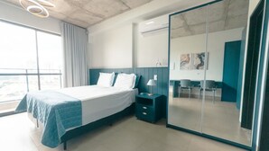 Habitació d'hotel moderna amb un llit gran, una tauleta de nit, un mirall i vista a la ciutat.