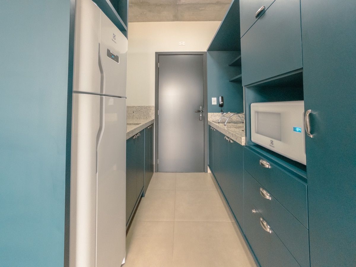 Eine schmale Küche mit Kühlschrank, Mikrowelle und Schränken.
