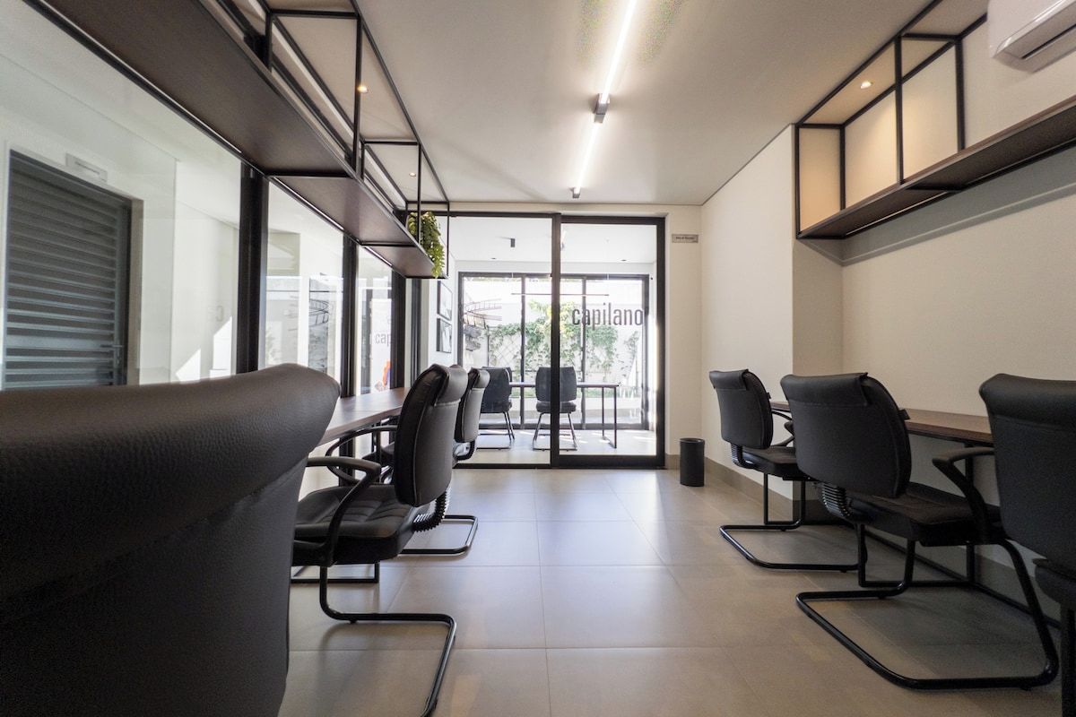 A modern conference room with black chairs, a long table, and large windows.