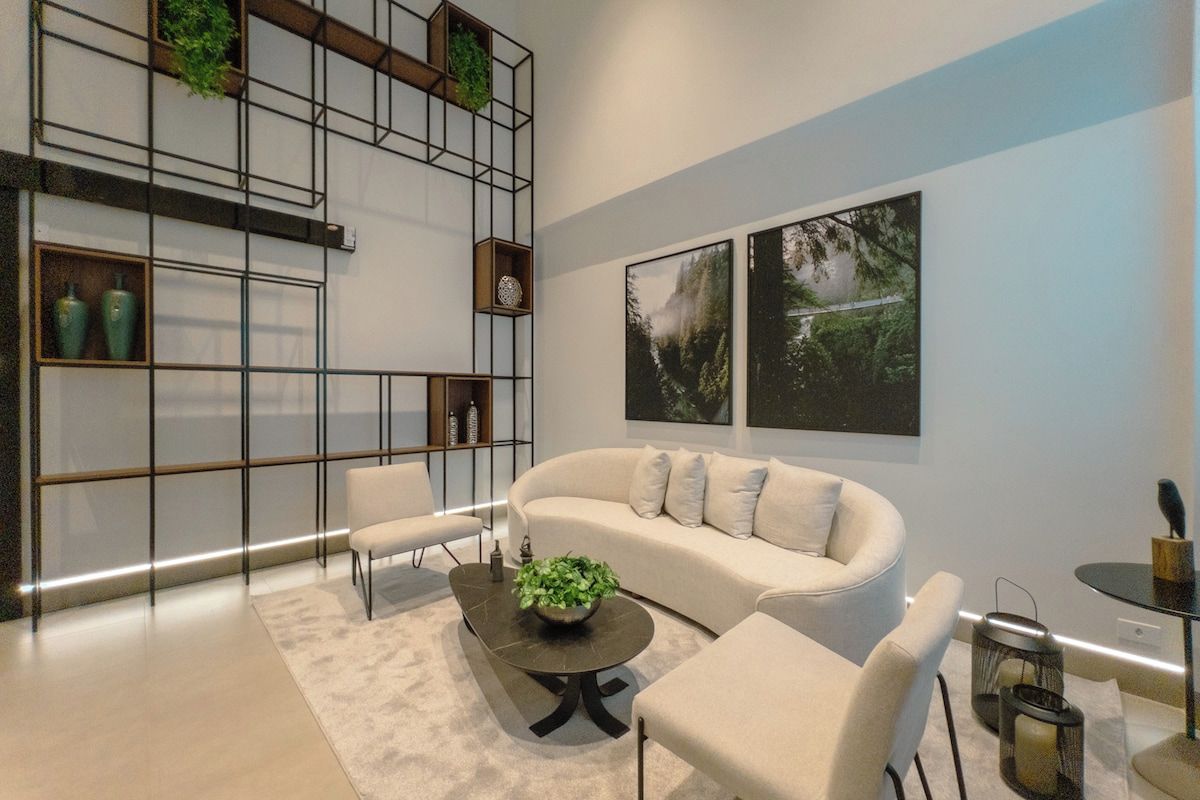 A modern living room with a sofa, chairs, a coffee table, and a built-in shelving unit with plants.