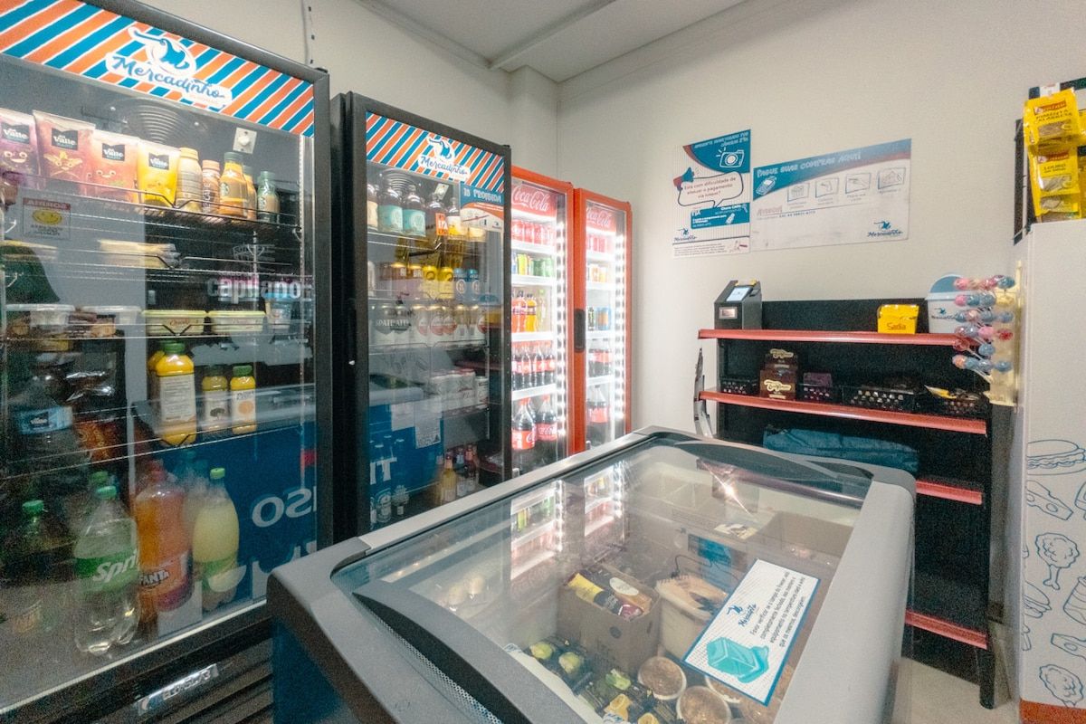 Un espace équipé de distributeurs automatiques proposant une variété de boissons, d’un présentoir réfrigéré et d’un réfrigérateur Coca-Cola.