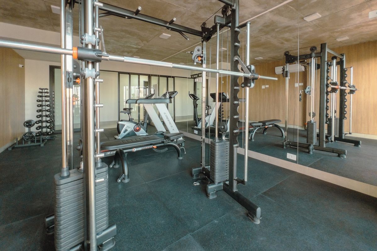 A gym with various exercise equipment, including a treadmill, weight machines, and a pull-up bar area.