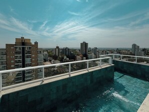 Ein Pool auf dem Dach mit Blick auf die Stadtlandschaft, umgeben von Hochhäusern.