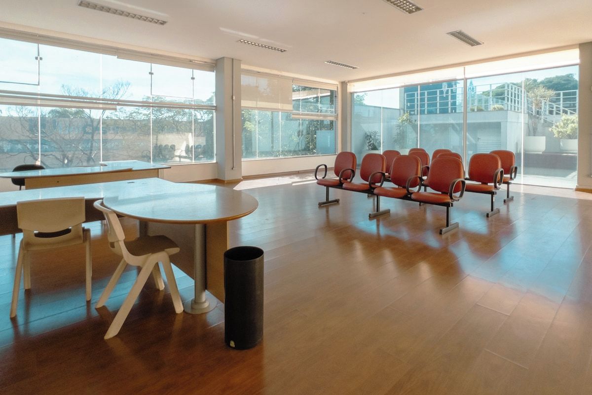 Una habitación amplia con una mesa grande y sillas, ventanas amplias y vistas al exterior.