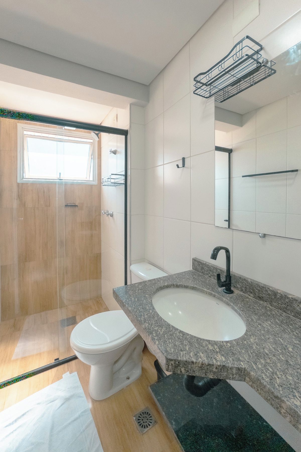 Uma casa de banho moderna com chuveiro, sanita e lavatório.