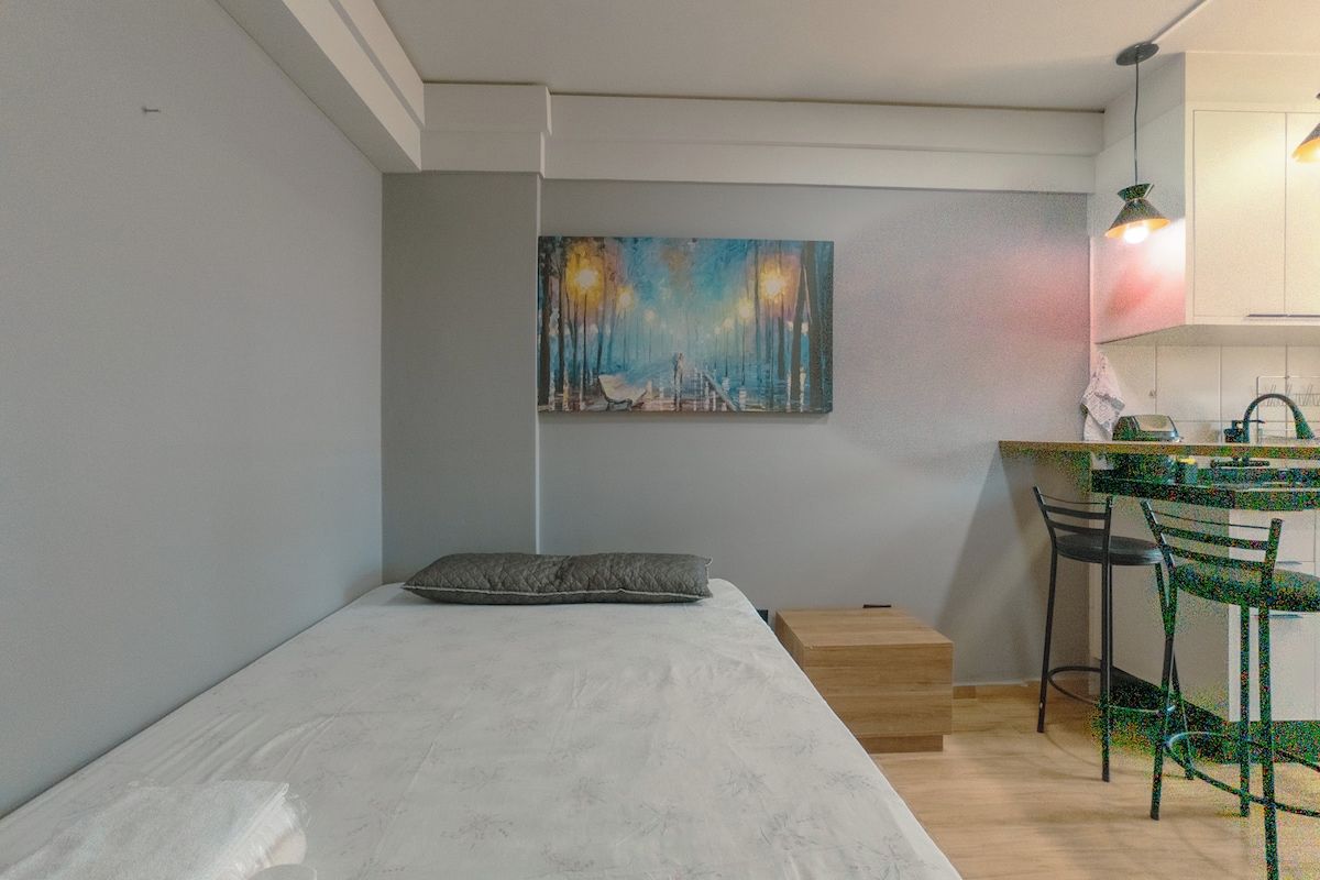 Un dormitorio minimalista con una cama individual, una mesita de noche pequeña y un cuadro en la pared.