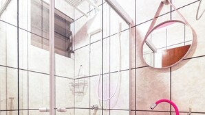 Casa de banho com chuveiro em cabine de vidro, lavatório cor-de-rosa e espelho.