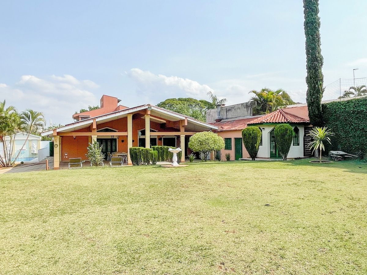 A two-story building with a covered patio area, a lawn, and a tall tree.