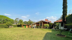 Um imóvel residencial com um gramado amplo, um alpendre coberto e um jardim bem cuidado.