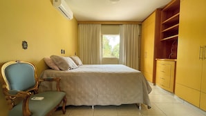 Quarto com cama, uma cadeira, guarda-roupa e ar condicionado.