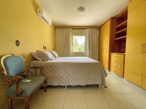 Een slaapkamer met een bed, een stoel, een kledingkast en een airconditioning.