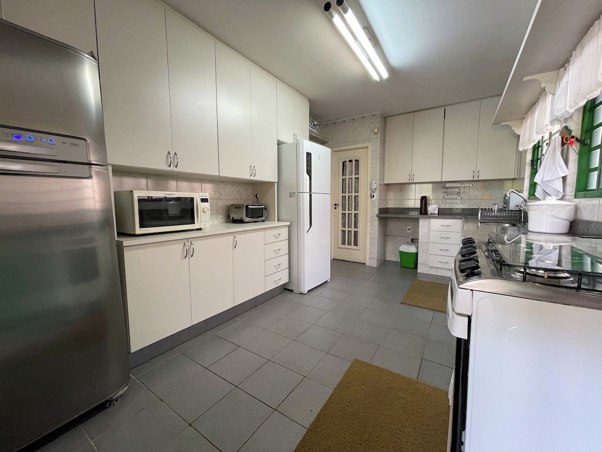 A kitchen with white cabinets, a stainless steel refrigerator, a microwave, a stove, and a door with a window.