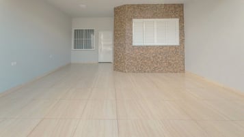 A spacious room with a tiled floor, a door, and a window with blinds.