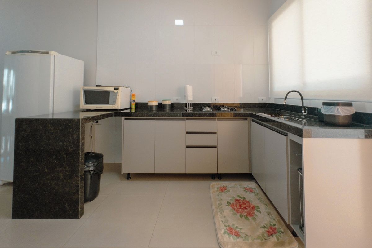 Cozinha compacta com micro-ondas, fogão, pia e arm ários.