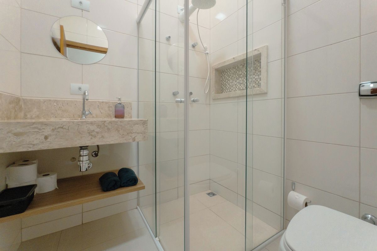 Um banheiro moderno com chuveiro envidraçado, pia de mármore e vaso sanitário.