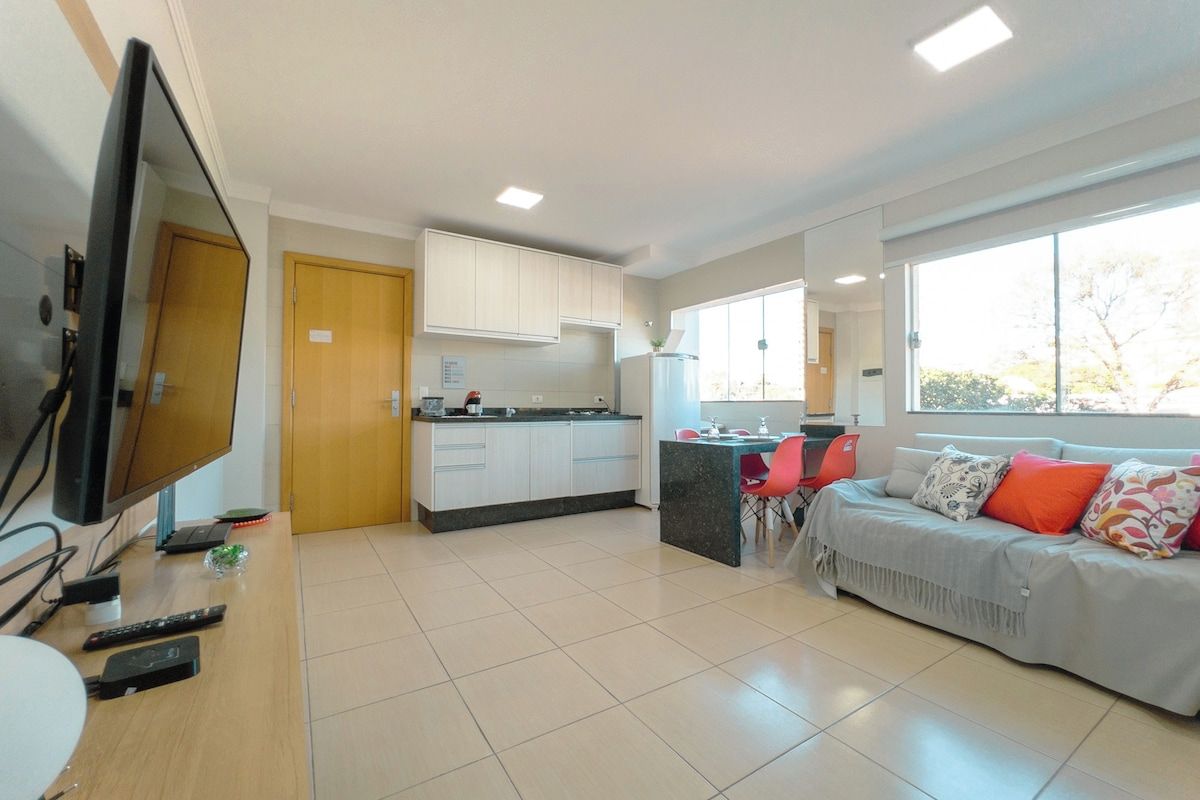 Sala de estar moderna com televisão, sofá e área de refeições.