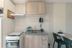 Une cuisine compacte équipée d’un four encastré, d’un évier et d’un coin repas avec une table et des chaises.