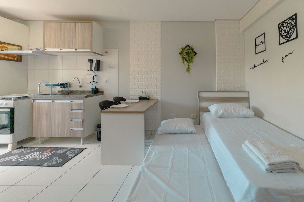 Una habitación funcional con kitchenette, una cama y un pequeño escritorio.