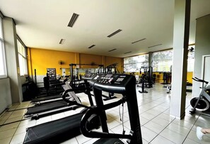 Une salle de sport équipée de tapis de course, d’appareils de musculation et d’un vélo d’appartement.