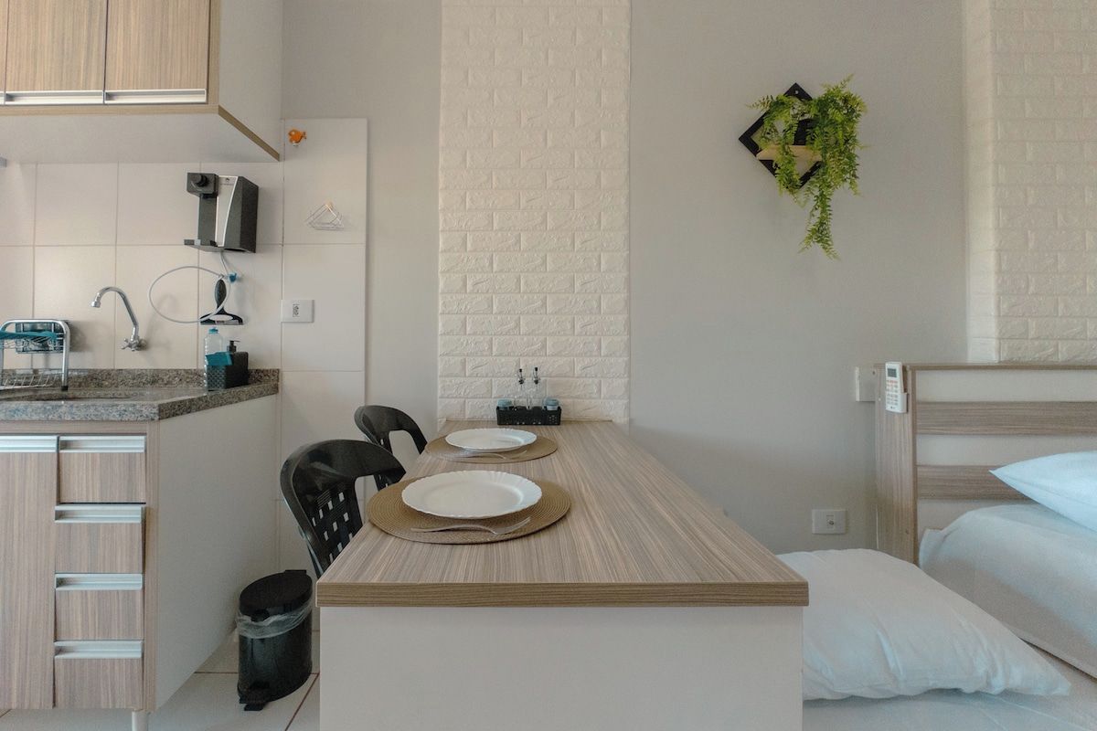 Una camera d'albergo compatta con angolo cottura, un letto e un piccolo spazio pranzo.