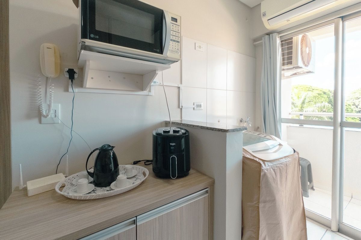 Une petite cuisine équipée d’un four à micro-ondes, d’une machine à café et d’un évier couvert.