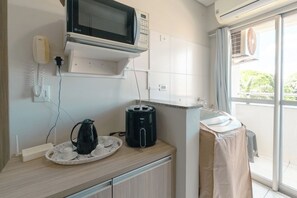 Une petite cuisine équipée d’un four à micro-ondes, d’une machine à café et d’un évier couvert.