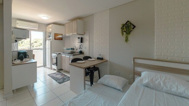 Een kleine kamer met een bed, een bureau en een kitchenette.