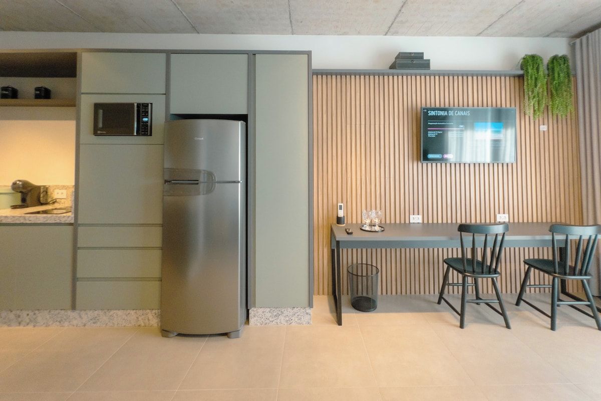 A modern kitchen with a built-in refrigerator, a microwave, and a wooden panel wall with a digital display.